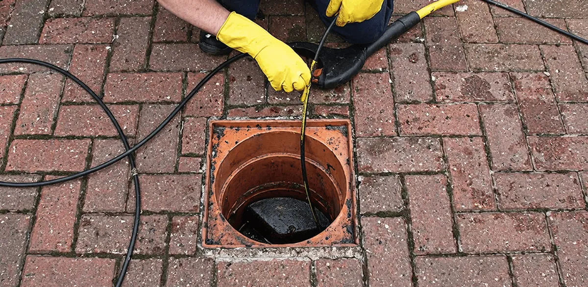 Drain cleaning technician using a drain snake to clear a clogged drain in Worcester, MA
