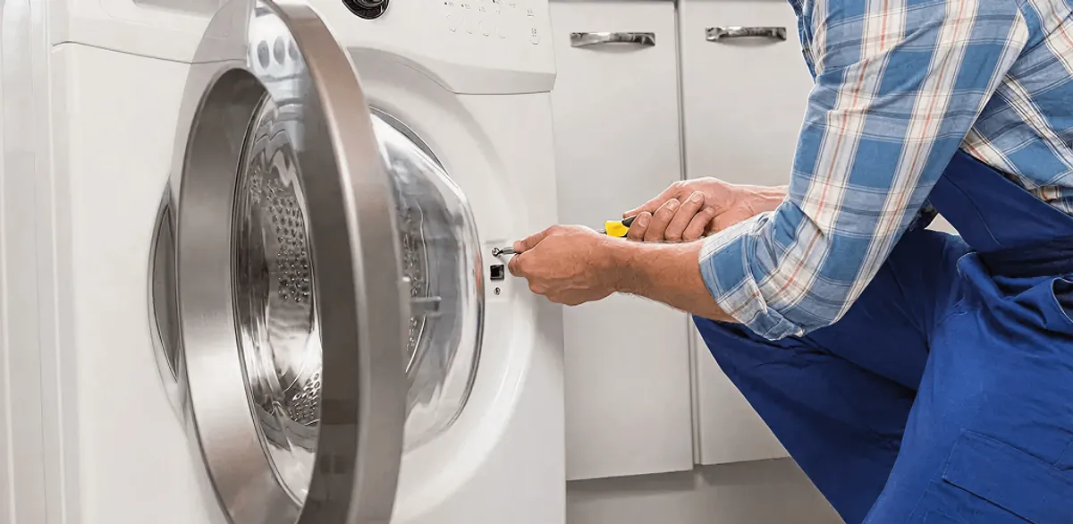 Handyman repairing a clothes dryer and checking electrical connections in Worcester, MA