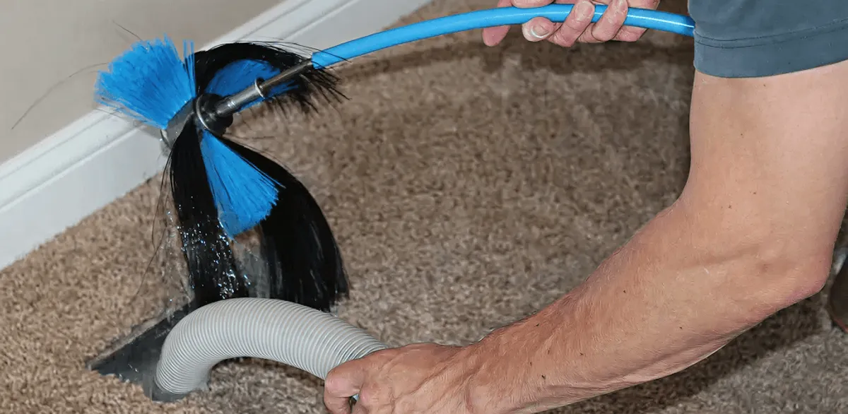 Dryer vent cleaning technician brushing lint from a vent line in Worcester, MA