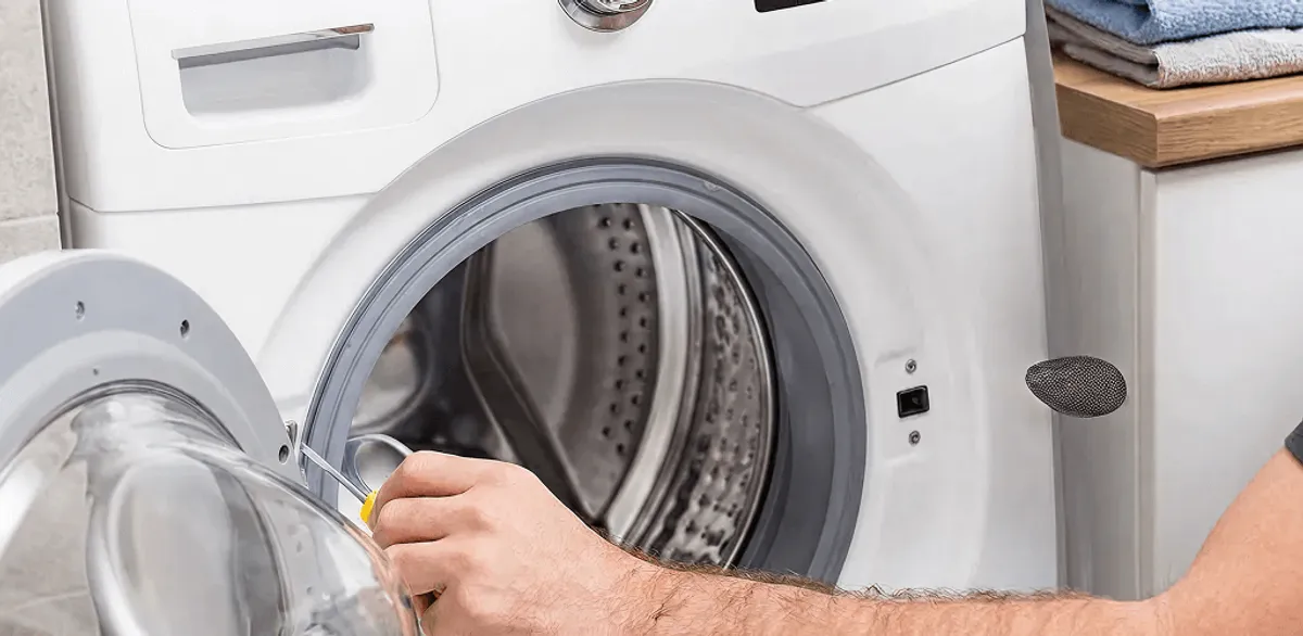 Handyman repairing a front-load washing machine and inspecting the drum in Worcester, MA